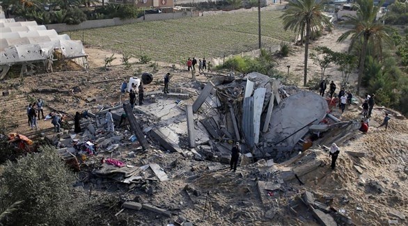 فلسطينيون حول أنقاض بيت دمره جراء القصف الإسرائيلي (رويترز)