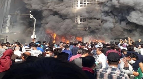 محتجون إيرانيون أمام مبنى حكومي التهمته النيران (تويتر)
