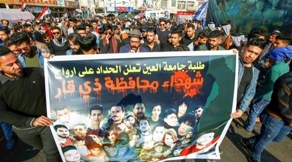 متظاهرون عراقيون يرفعون لافتة عليها صوراً لقتلى سقطوا في الاحتجاجات (أرشيف)