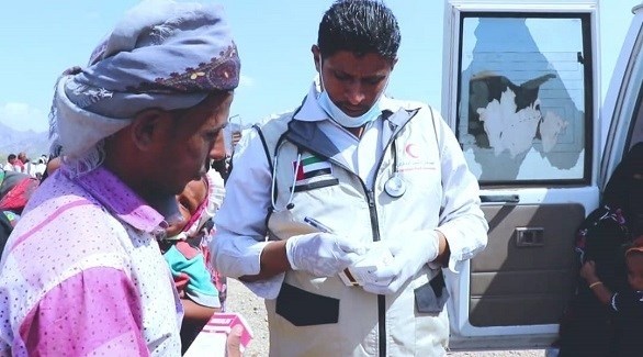 متطوع من الهلال الأحمر الإماراتي مع مستفيدين من المساعدات في اليمن  (وام)