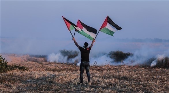 فلسطيني يحمل أعلام بلاده خلال إحدى التظاهرات (أرشيف / غيتي)