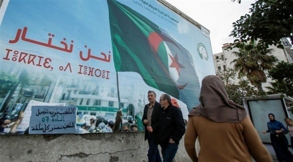جزائريون يمرون من أمام لوحة دعائية للانتخابات الرئاسية (أرشيف)