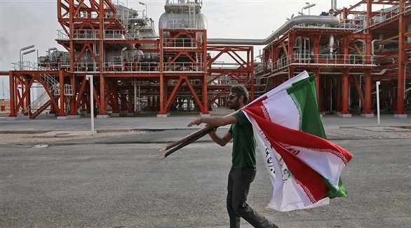 شخص يحمل أعلاماً إيرانياً بالقرب من منشأة صناعية (أرشيف)
