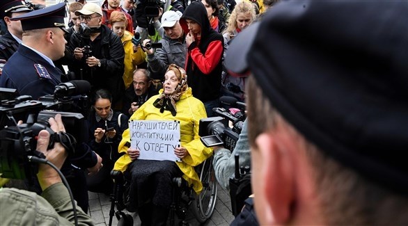 ناشطة مقعدة تحمل يافطة "احترموا الدستور" في تظاهرة وسط موسكو (أ ف ب)