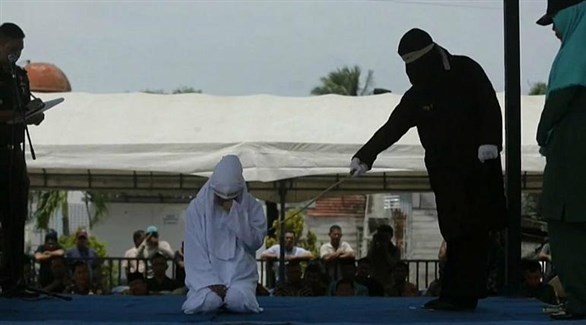 جلاد يجلد امرأة أمام مسجد في مدينة باندا عاصمة إقليم أتشيه الإندونيسية (أف ب)