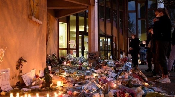 ورود وشموع بالقرب من مدخل المدرسة التي قتل فيها الاستاذ في باريس (أرشيف)