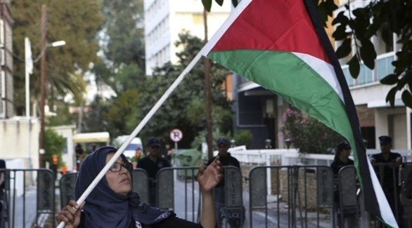امرأة ترفع العلم الفلسطيني إلى جانب السفارة الإسرائيلي في نيقوسيا (أرشيف / أ ب)