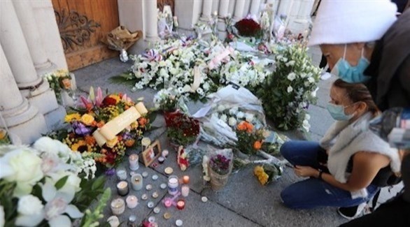 سيدتان تضعان زهوراً أمام كنيسة نوتردام بنيس بعد هجوم الأمس (أ ف ب)