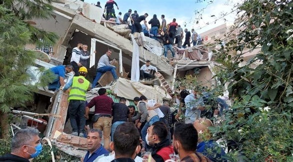 أتراك بين أنقاض مبنى هدمه الزلزال بحثاً عن ناجين محتملين في إزمير (تويتر)