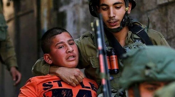 عنصر من الجيش الإسرائيلي يعتقل طفل فلسطيني (أرشيف)