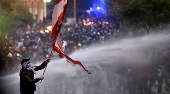 متظاهر يحمل العلم اللبناني وسط تظاهرات بيروت (اي بي ايه)