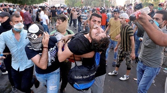 محتجون عراقفيون يسعفون متظاهراً مصاباً في المواجهات مع الأمن (أرشيف)