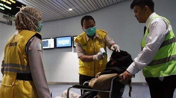 عاملون صحيون يتأكدون من الوضع الصحي لمسافر في أحد المطارات (أرشيف)