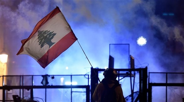 متظاهر يرفع العلم اللبناني أمام السياج الأمني وسط بيروت (اي بي ايه)