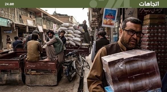 عمال ينقلون سلعاً في بازار للبضائع الإيرانية في ولاية هرات الأفغانية (أرشيف)