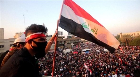 محتج عراقي يرفع علم بلاده في بغداد (إ ب أ)