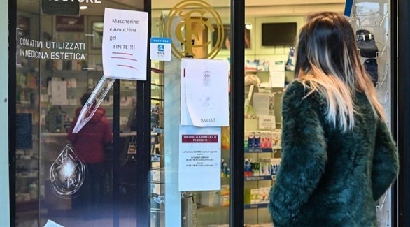 إيطالية أمام صيدلية تطالع إعلاماً بنفاد الأقنعة الواقية وسوائل التطهير (أرشيف)