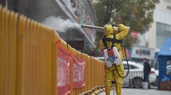 عامل يعقم أحد شوارع مدينة ووهان الصينية (روتيرز)