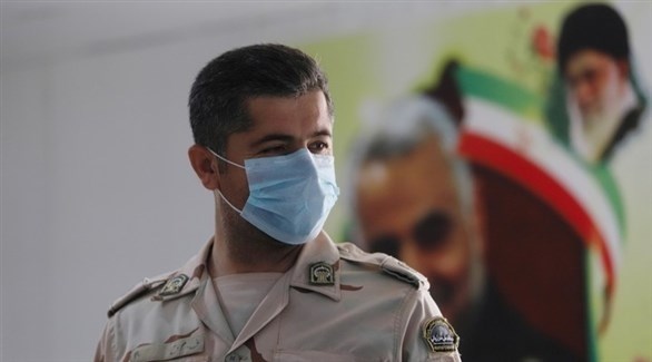 عسكري إيراني يضع كمامة أمام صورة لقائد فيلق القدس الراحل الجنرال قاسم سليماني.(أرشيف)