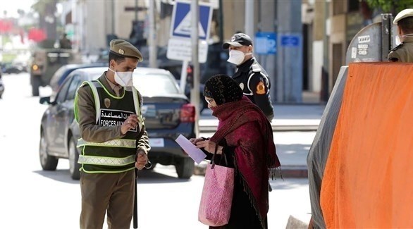 شرطي مغربي يتفحص أوراق سيدة بعد إعلان حظر التجوال (أرشيف)