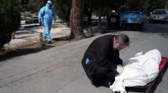 إيراني إلى جانب جثة ضحية لكورونا قبل دفنه (أرشيف)