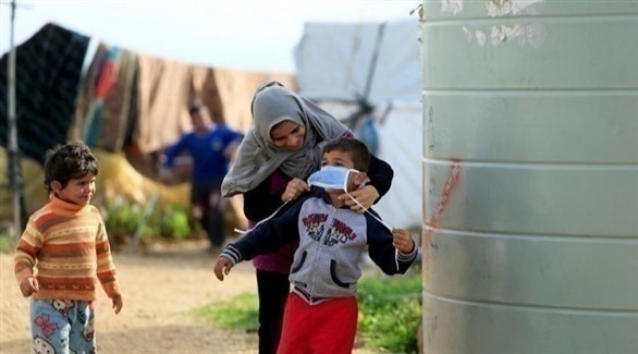 لاجئة سورية تضع كمامة على وجه ابنها وقاية من كورونا (أرشيف)