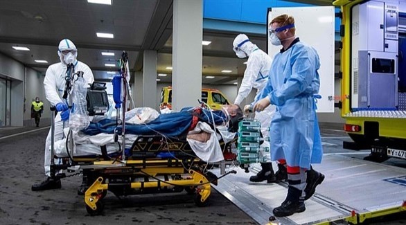 مسعفان وعامل في المجال الصحي ينقلون مصاباً بكورونا إلى مستشفى (أرشيف)