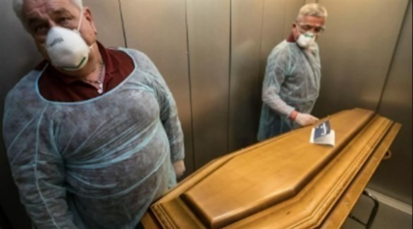 عاملان بقطاع الصحة الفرنسي ينقلان جثة متوفى بكورونا للدفن (أرشيف)