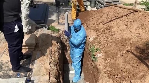 عامل في قبر أحد ضحايا كورونا في إيران تمهيداً لدفنه (أرشيف)