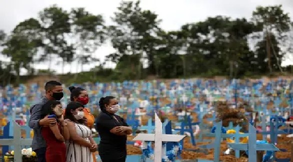 عائلة برازيلية في مقبرة بعد دفن احد ضحايا كورونا (رويترز)
