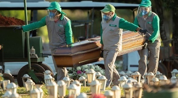 عاملون في قطاع الصحة البرازيلي ينقلون جثة ميت بكورونا للدفن (إ ب أ)