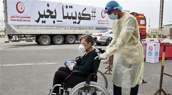 مساعدة امرأة عند أحد مراكز فحص الكورونا في الكويت (أرشيف)