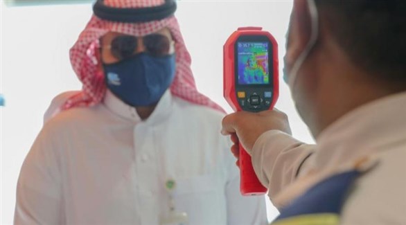 عامل يتأكد من حرارة موظف قبل دخوله مبنىً حكومياً في السعودية (د ب أ)  