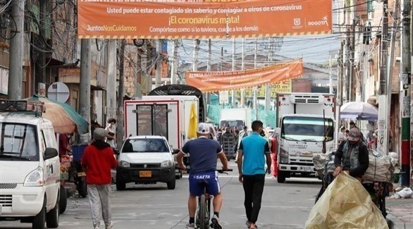 كولومبيون في بوغوتا تحت يافطة كتب عليها "فيروس كورونا يقتل" (إ ب أ)
