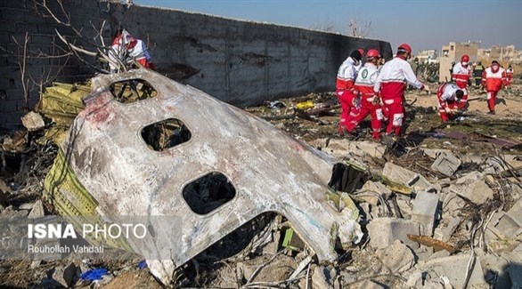 عمال انقاذ أمام حطام الطائرة المنكوبة (أرشيف / إيسنا)