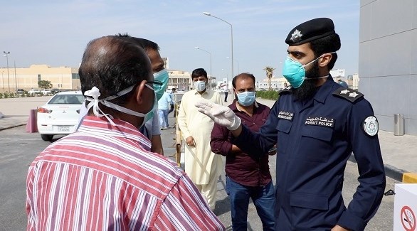 شرطي يتحدث إلى مراجعين في مركز فحص صحي كويتي (أرشيف)