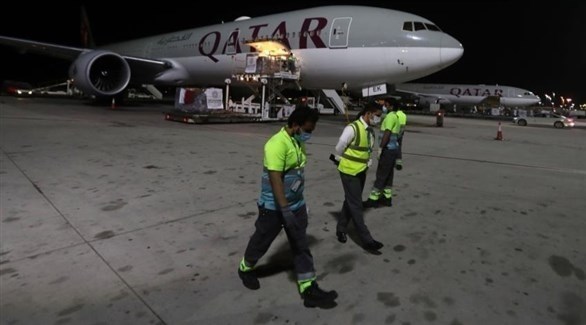 موظفون أمام طائرة للخطوط الجوية القطرية في مطار الدوحة (أرشيف)