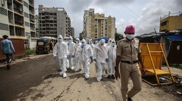 شرطي هندي يتقدم عدداً من العاملين بقطاع الصحة المختص بمواجهة كورونا (إ ب أ)