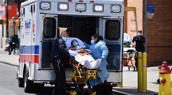 مسعفان أمريكيان ينقلان مصاباً بكورونا إلى سيارة إسعاف (أرشيف)