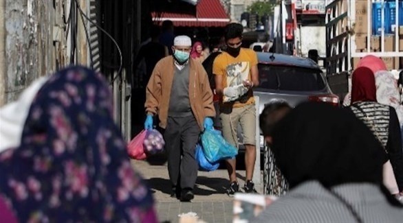 فلسطينينون يرتدون كمامات أثناء تسوقهم (أ ف ب)