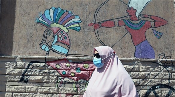 سيدة مصرية تمر من أمام جدارية مرسوم عليها نقش فرعوني (إ ب أ)