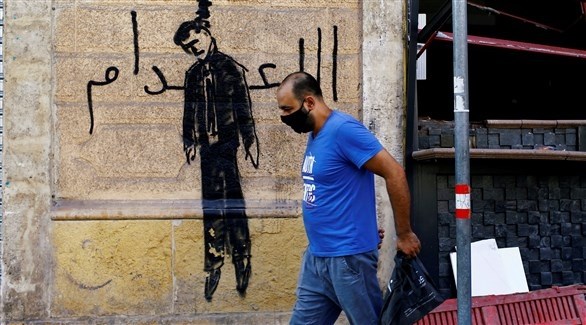 رجل يمر بجانب جدارية تطالب بإعدام المسؤولين، على أحد جدران بيروت المتضررة (رويترز)