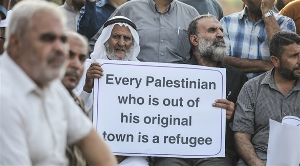 مسن فلسطيني يحمل لافتة كتب عليها "كل فلسطيني خارج قريته الأم هو لاجئ" (أرشيف)
