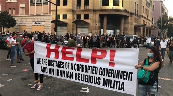 شابان لبنانيان يرفعان لافتة عليها "النجدة! نحن رهائن حكومة فاسدة وميليشيا إيرانية" (أرشيف)