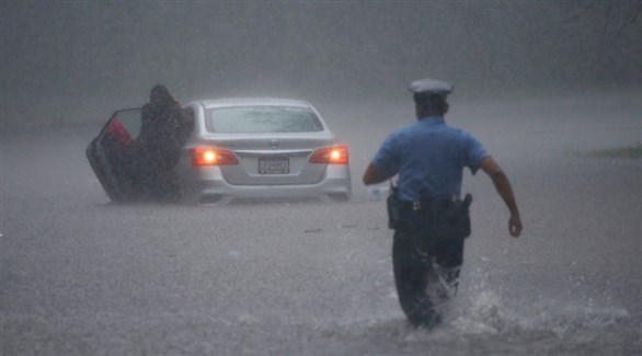 شرطي في فيلاديلفيا يتجه نحو سائق سيارة عالق في المياه لمساعدته (رويترز)