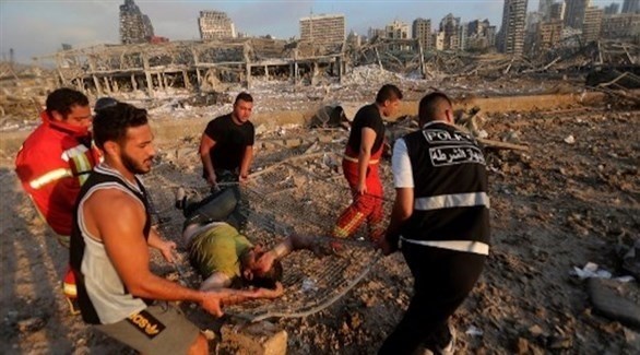 مسعفون ومنقذون لبنانيون يجلون مصاباً بعد انفجار بيروت (أ ف ب)