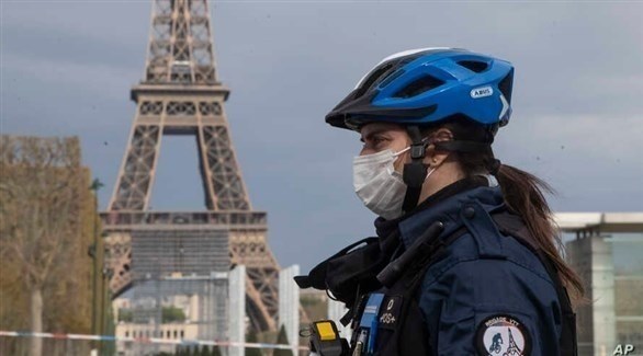 شرطية ترتدي كمامة أثناء مرورها بجانب برج إيفل (أرشيف)