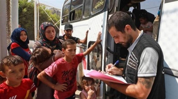 عنصر من الأمن اللبناني يسجل لاجئين سوريين قبل صعودهم إلى حافلة (أرشيف)