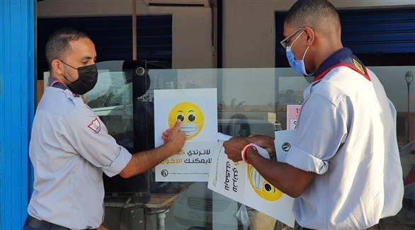 عناصر كشفية توزع الملصقات للتوعية من كورونا في طرابلس الليبية (أ ف ب)