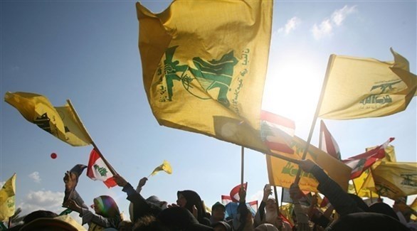 أشخاص يرفعون أعلام ميليشيا حزب الله في أحد التجمعات (أرشيف)